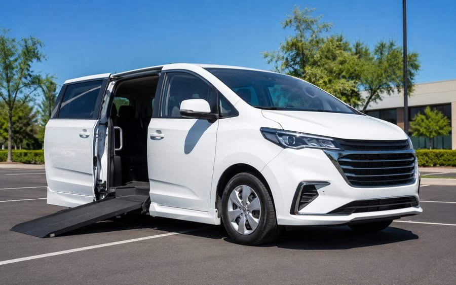 A white wheelchair-accessible transport van with its side ramp deployed.